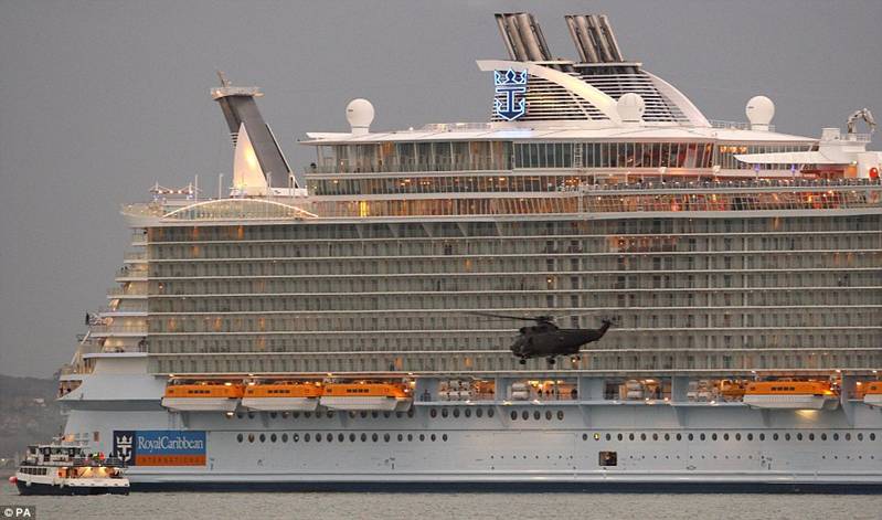 A Royal Navy Sea King helicopter
                              makes a low fly-past of the Oasis of the
                              Seas as she enters the Solent 