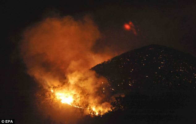 Trail of
        destruction: The leading edge of the fire continues on its path
        at the base of a hill in Santa Eulalia, while spot fires show
        where the blaze has been along the hillside