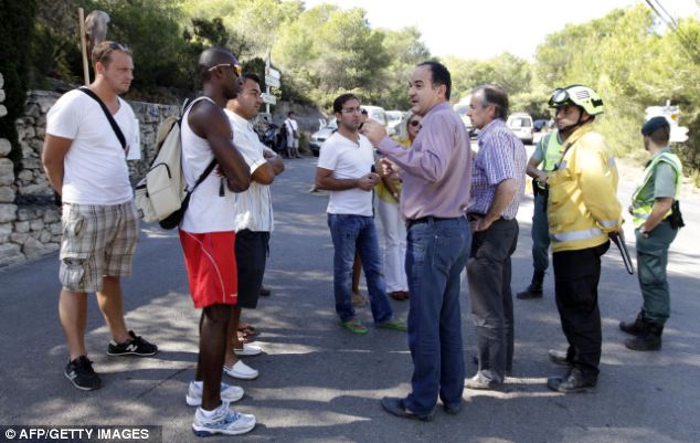Waiting for
        information: The Mayor of Santa Eularia, Vicent Mari (centre),
        speaks with local residents after fires in their neighbourhoods.
        Emergency services are looking after evacuated locals