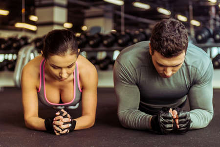 52489040-attractive-young-muscular-man-and-woman-doing-plank-exercise-while-working-out-in-gym.jpg