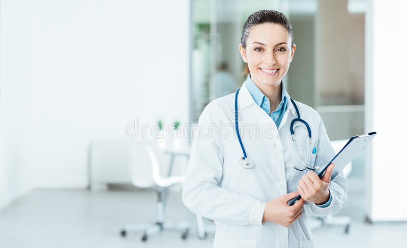 smiling-female-doctor-holding-medical-records-lab-coat-her-office-clipboard-looking-camera-56673035.jpg