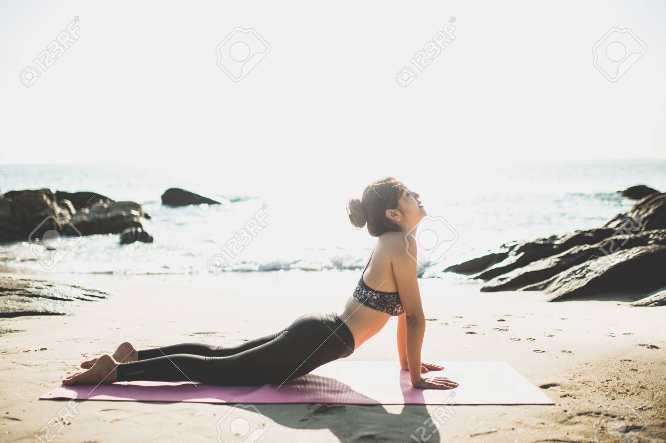 76368833-young-woman-doing-yoga-on-the-beach-in-morning-park.jpg